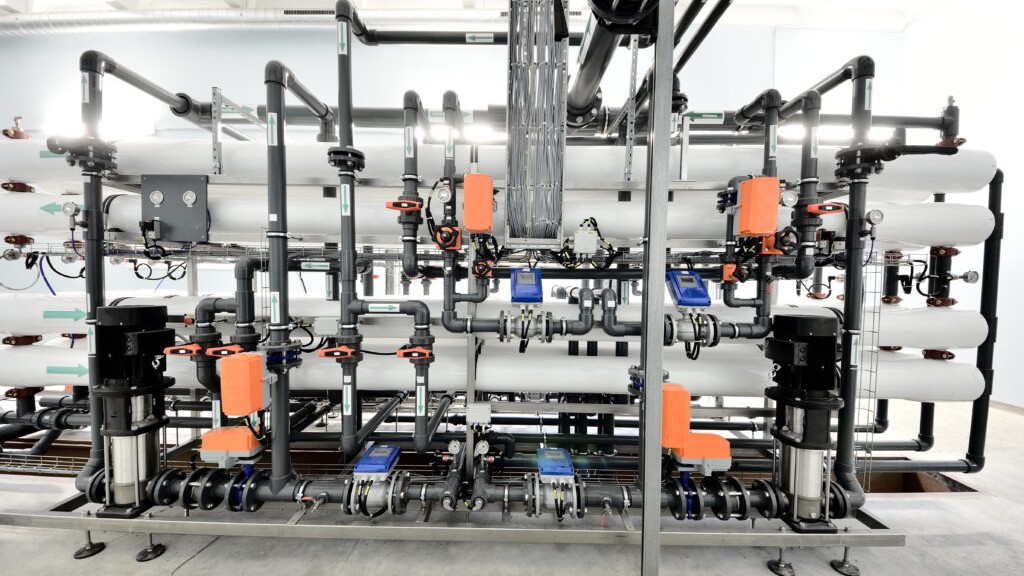 Station d'osmose inverse professionnelle : membranes, pompes haute pression et tuyauterie dans un local technique